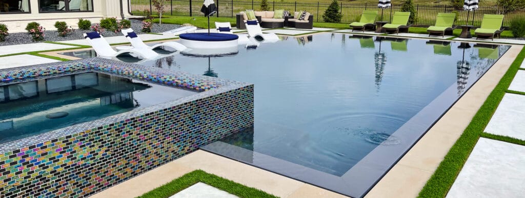 Sleek, full-perimeter overflow pool with glass-tiled spa.