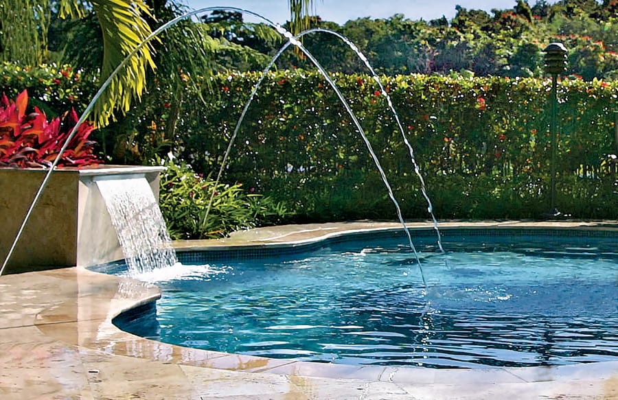 Glass-like arcs of water falling onto surface of swimming pool.