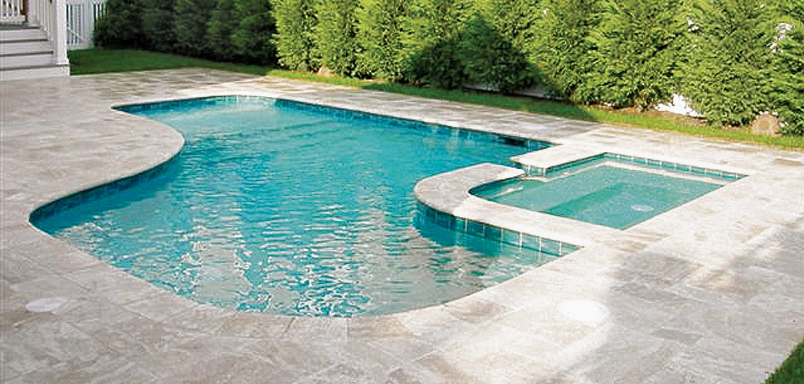 Backyard swimming pool with square spa with a rounded corner.