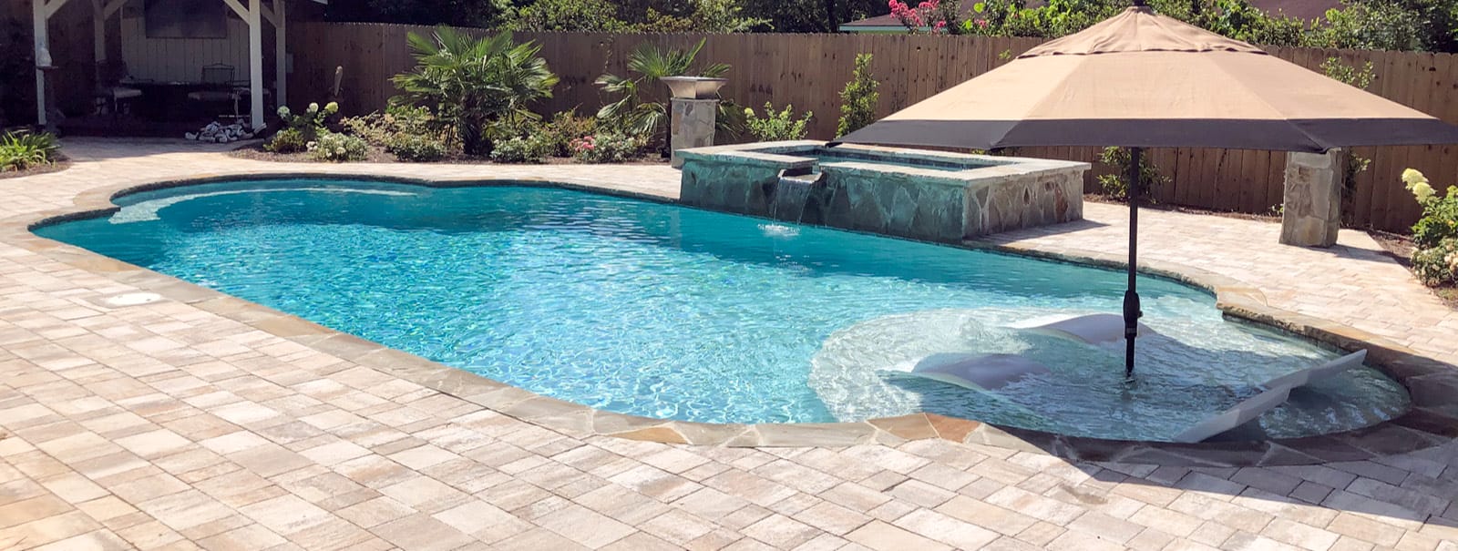 Inground pool with tanning ledge and patio umbrella in pensacola.