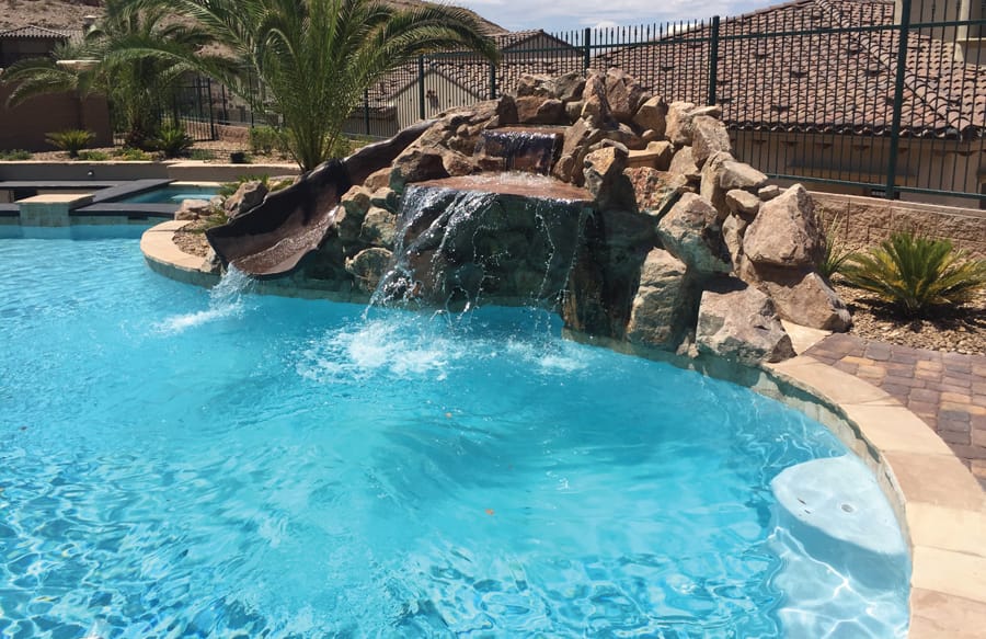 Stone grotto waterfall with integrated slide in Henderson backyard.