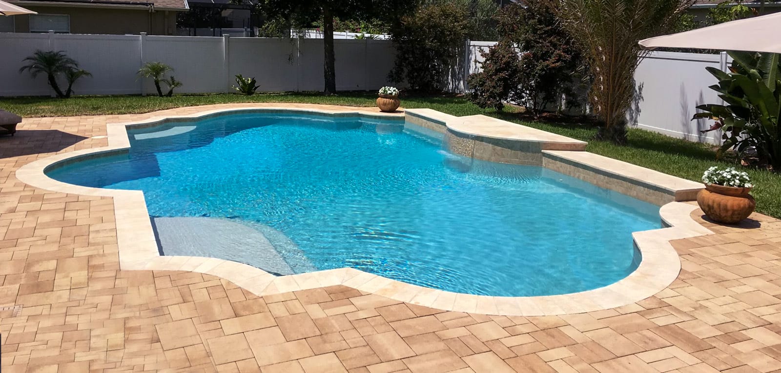Inground pool with a modified Roman shape and raised beam wall.
