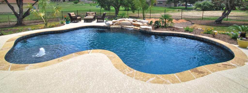 Curvy inground pool with deep blue interior finish in Ft. Worth.