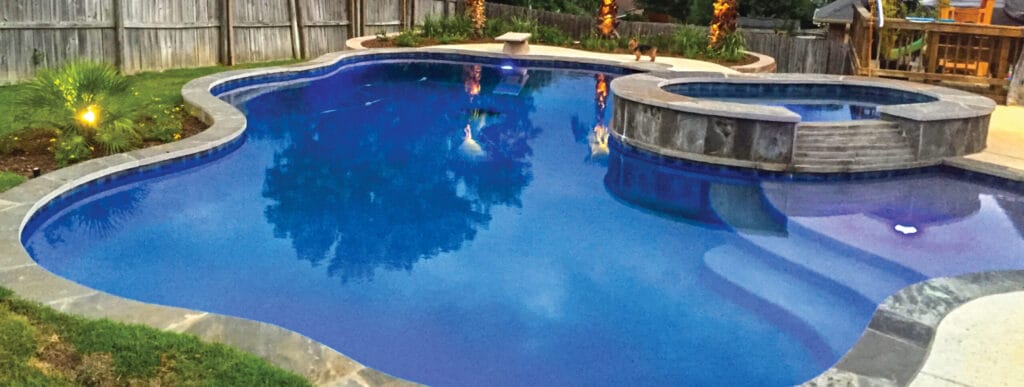 Freeform swimming pool with diving board and deep blue interior.