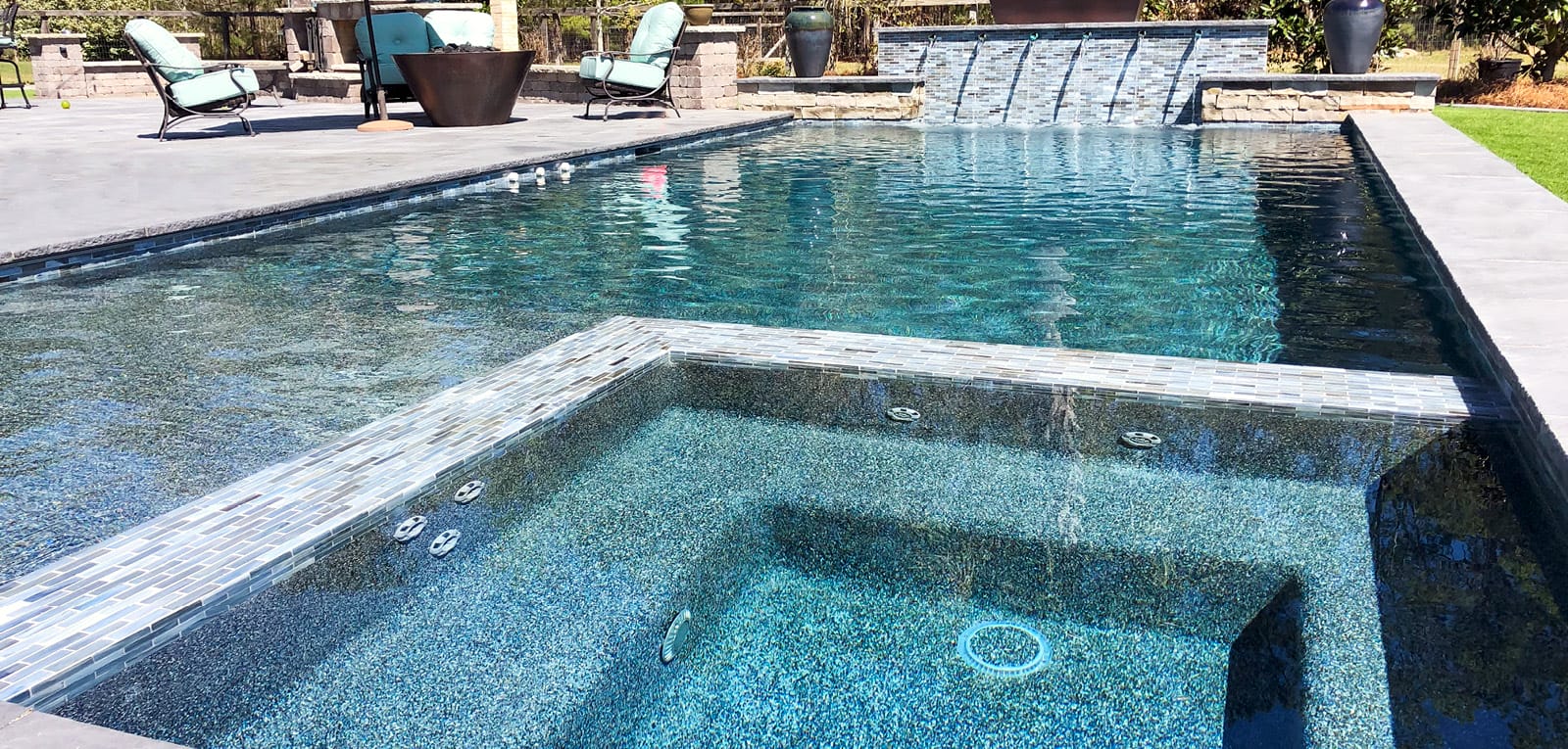 Square interior spa on a rectangular swimming pool.