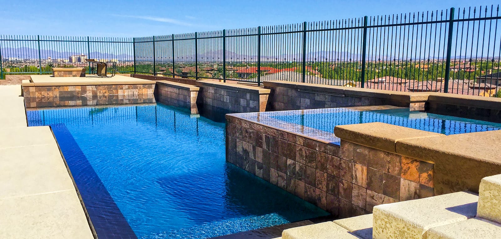 Full-perimeter overflow pool with custom rectangle shape in a fenced yard.