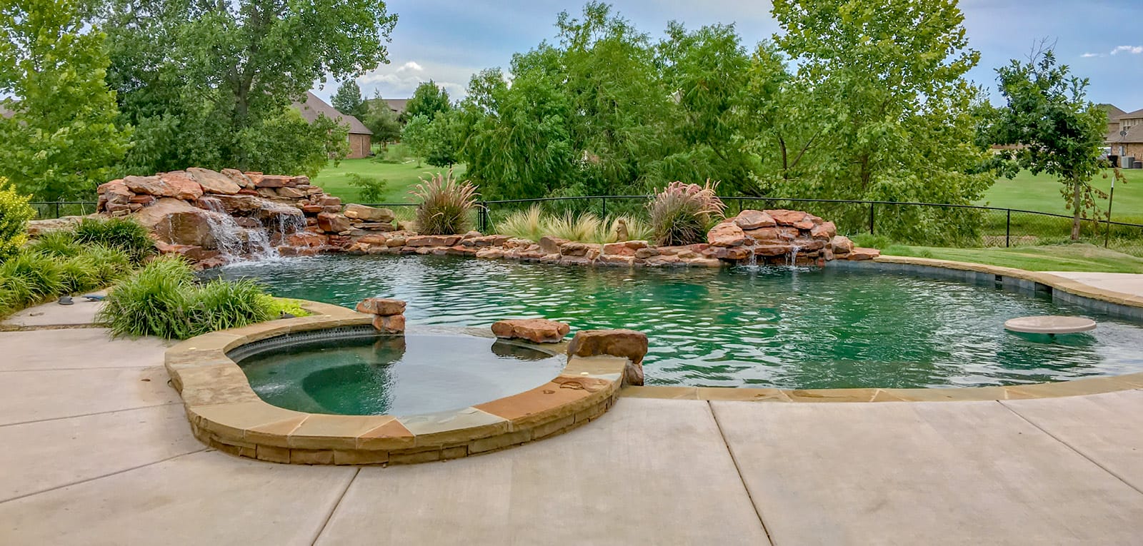 Custom pool with a lagoon motif and organic-shaped spa with small accent boulders.