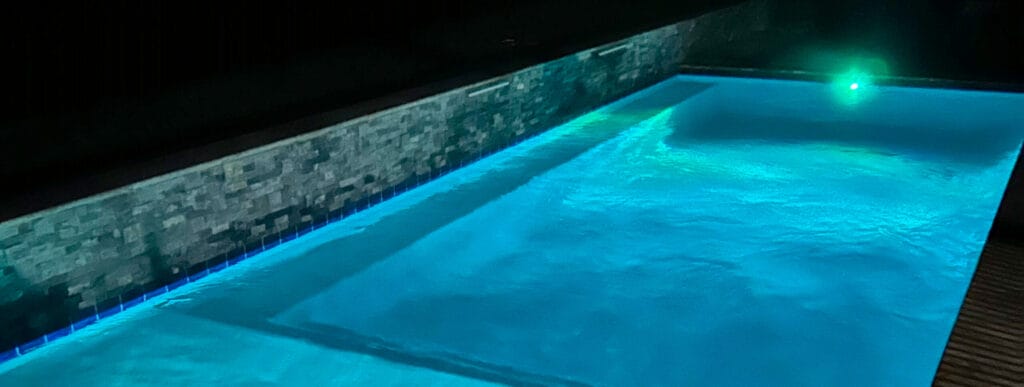 Rectangular-shaped pool illuminated at night.
