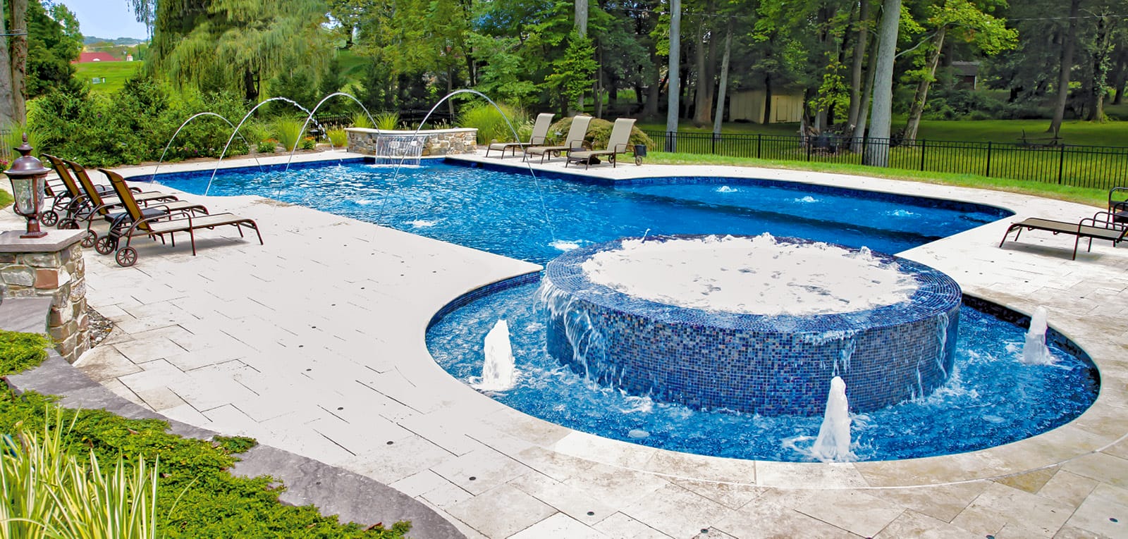 Custom geometric inground pool with round bubbling spa and fountains.
