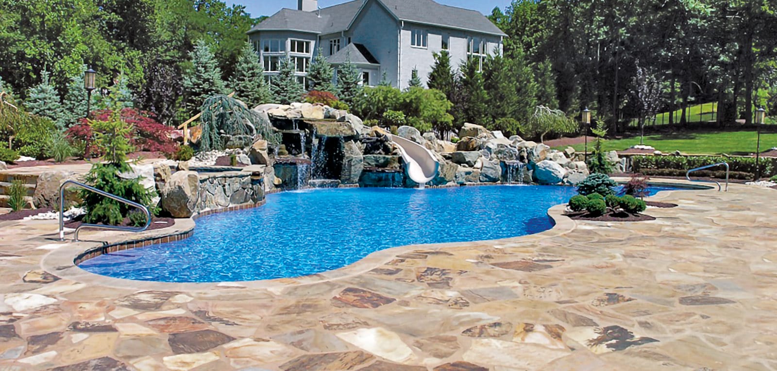 Organic-shaped pool with large rock waterfall and integrated slide.