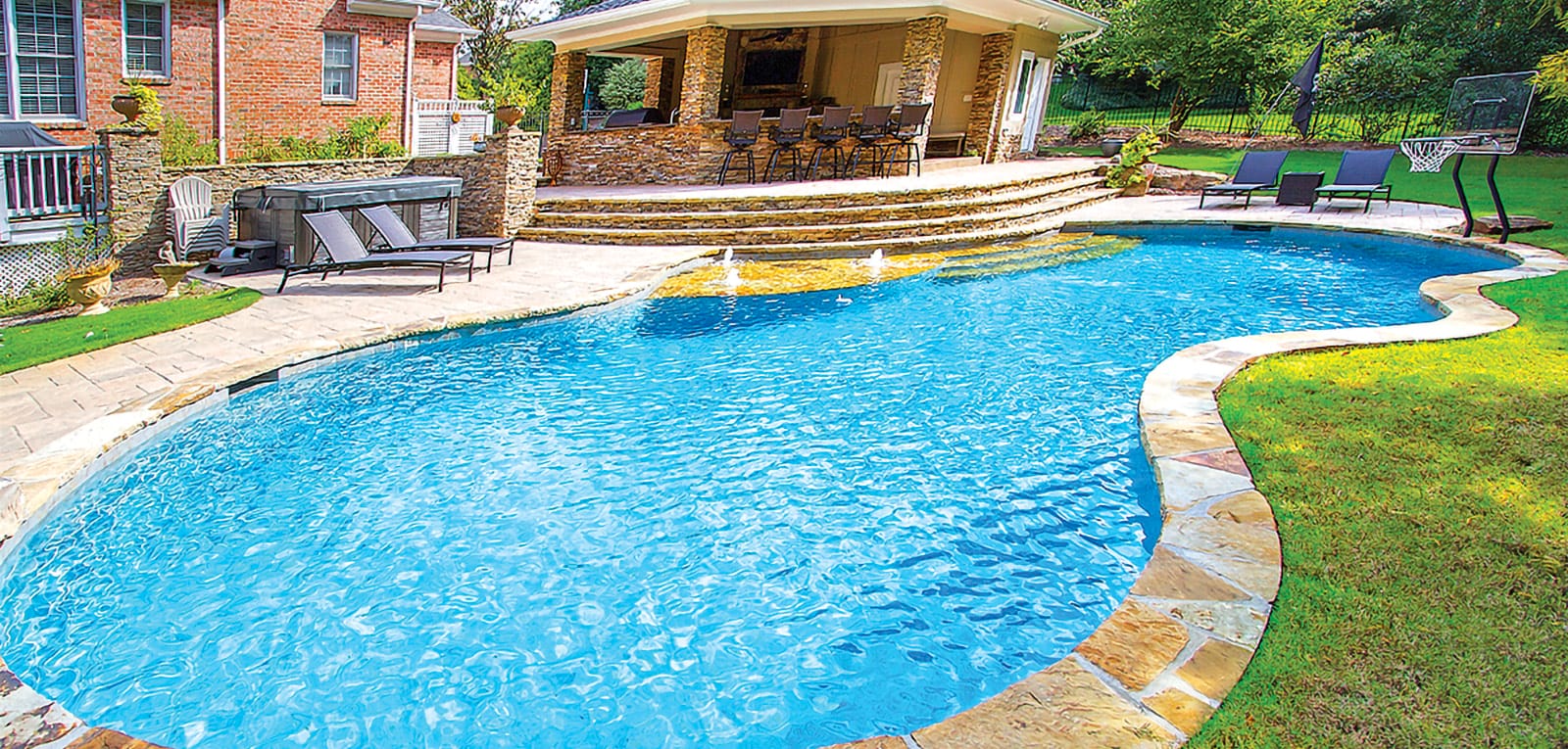 Free-form gunite pool with flagstone perimeter coping and outdoor kitchen.