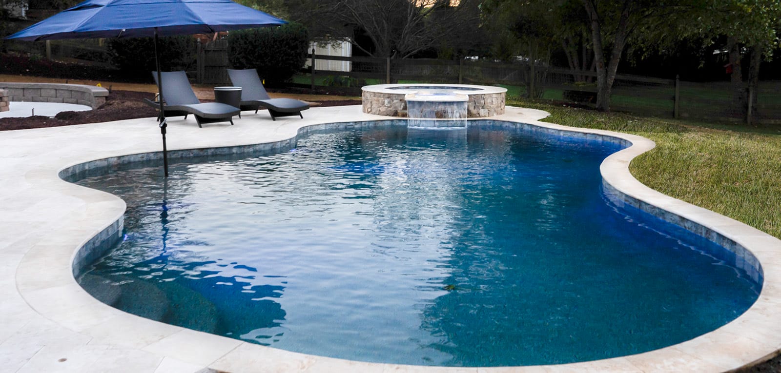 Free-form swimming pool with deep blue interior and raised spa.