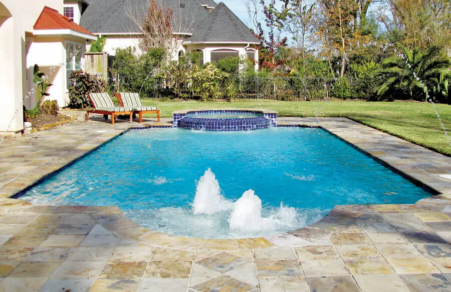 Roman swimming pool with round spa and bubbler fountains on tanning ledge in Texas.