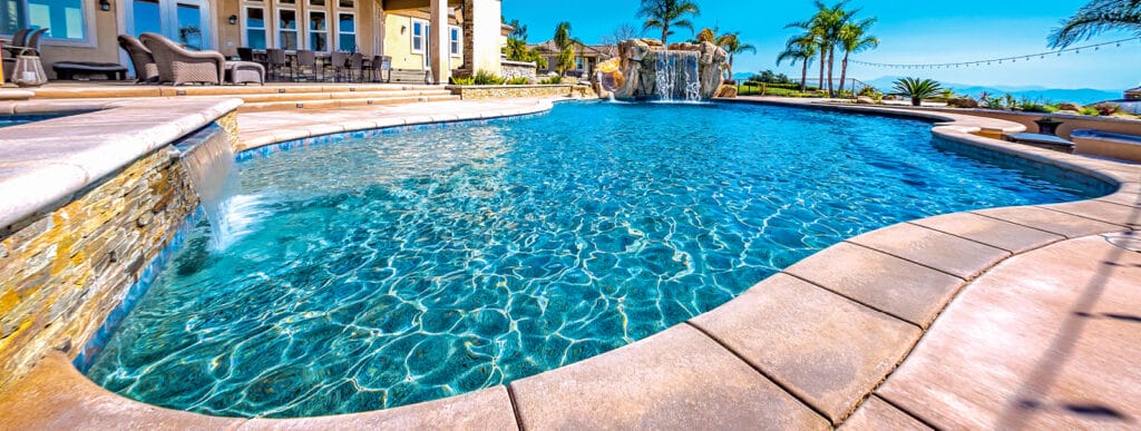 Curvy Carlsbad swimming pool with stack-stone wall with cascade water feature.