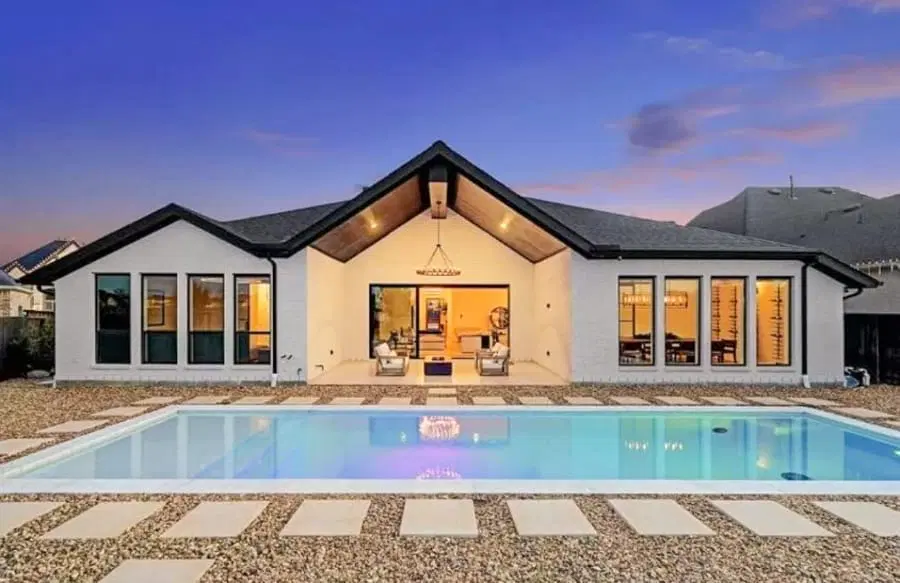Rectangle inground pool with lighting at sunset in a Houston residence.