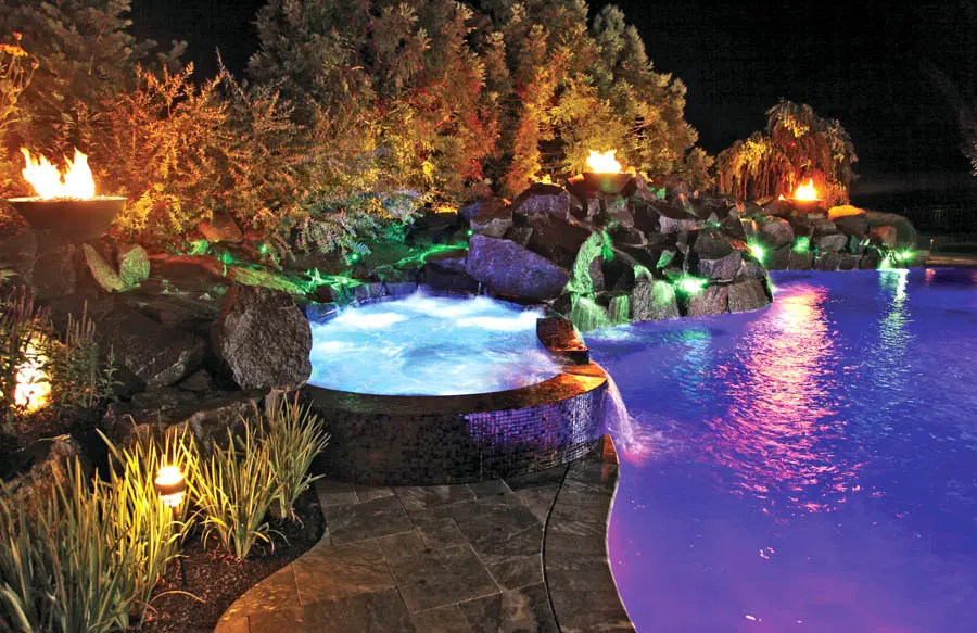 Custom spa, rock waterfall, and fire bowls on inground swimming pool.