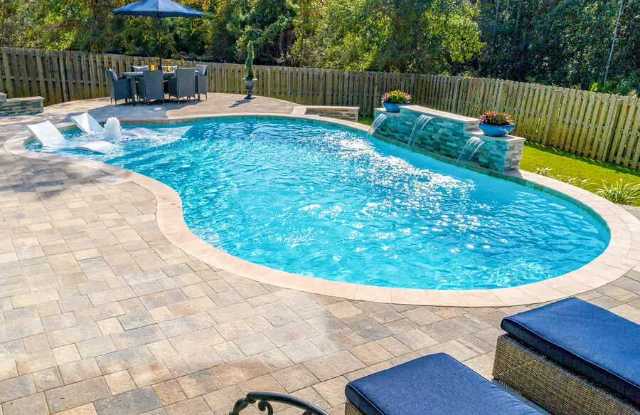 Mobile gunite pool with paver deck and sun shelf.