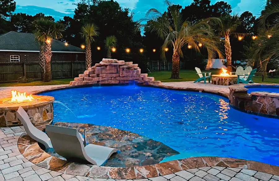 Free-form pool with rock waterfall and flagstone coping at night in Pensacola.