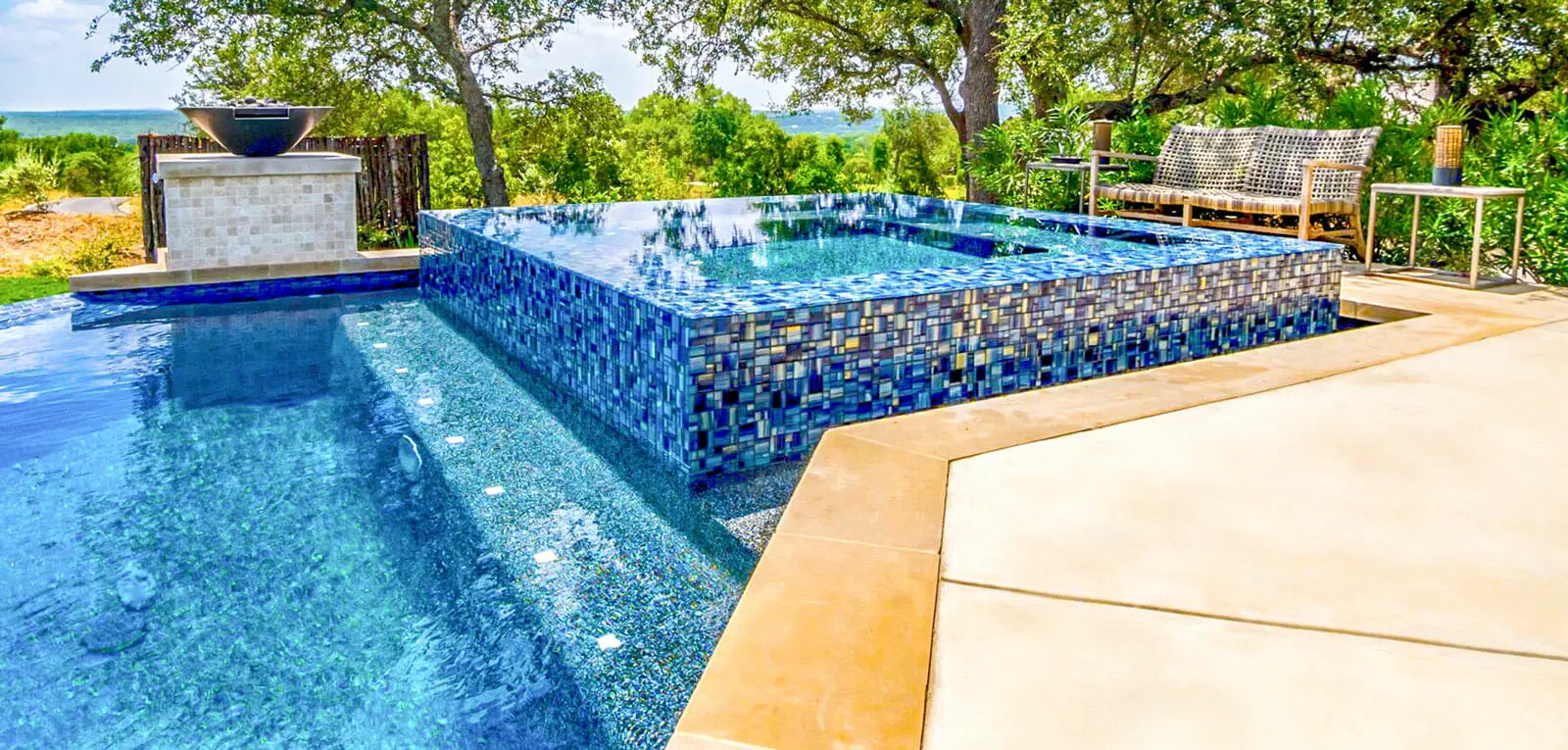 Square rimflow spa with blue tile on inground pool.
