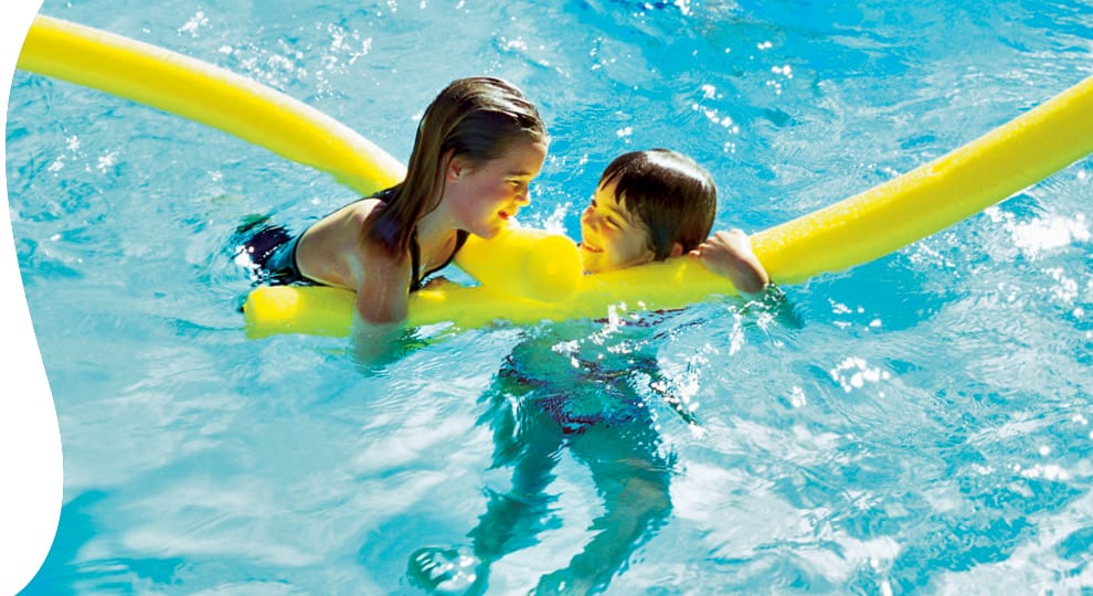 Young girls in swimming pool with yellow foam toys.