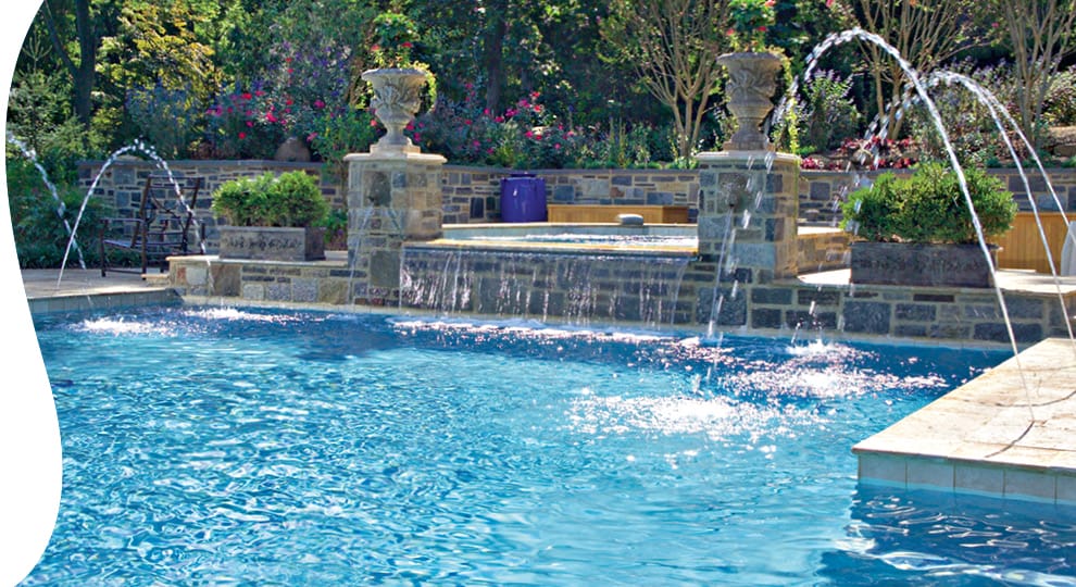 Swimming pool and spa with arching fountains splashing onto the pool surface.