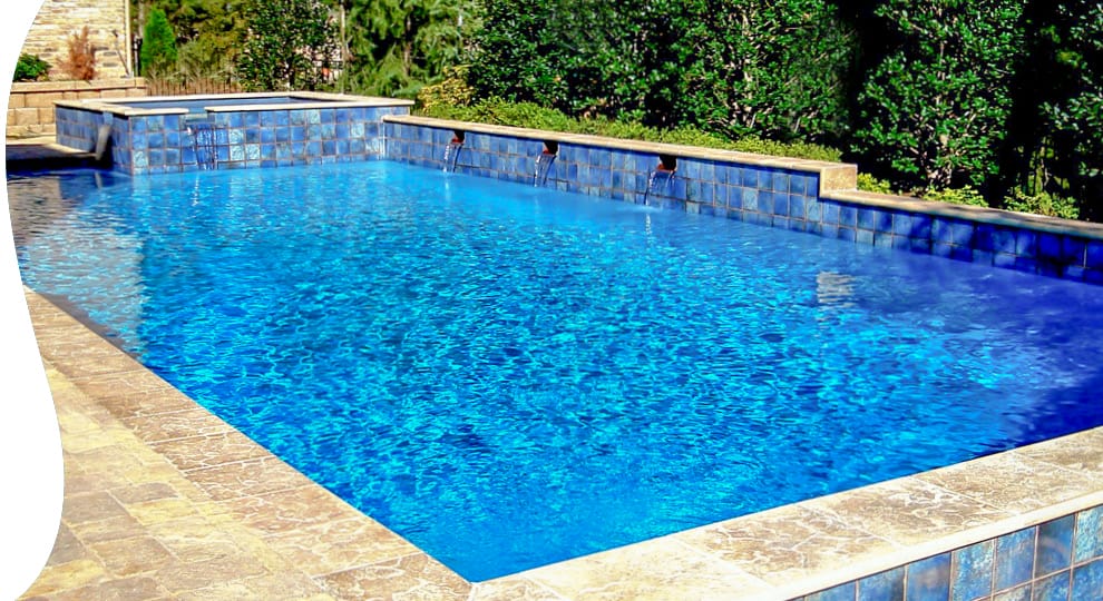 Elevated square spa on rectangular inground pool with water features.