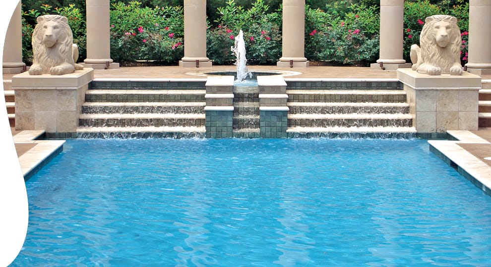 Custom pool with two ion statues, decorative steps and a tall bubbling fountain.
