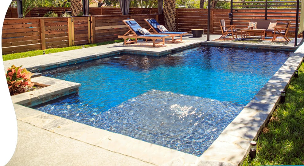 Swimming pool with square tanning ledge in backyard.