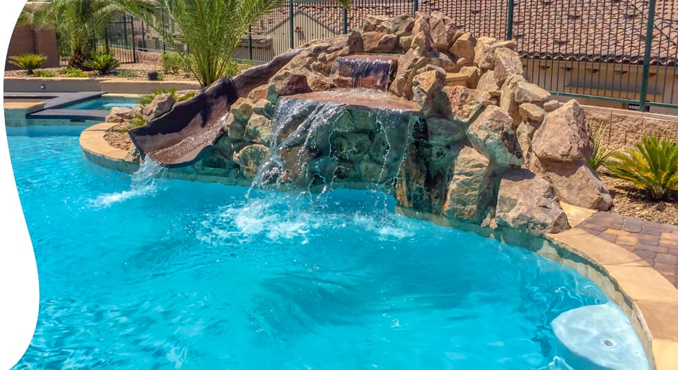 Rock waterfall with integrated slide on swimming pool.