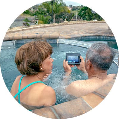 Man and woman couple in custom spa with man holding remote control device.