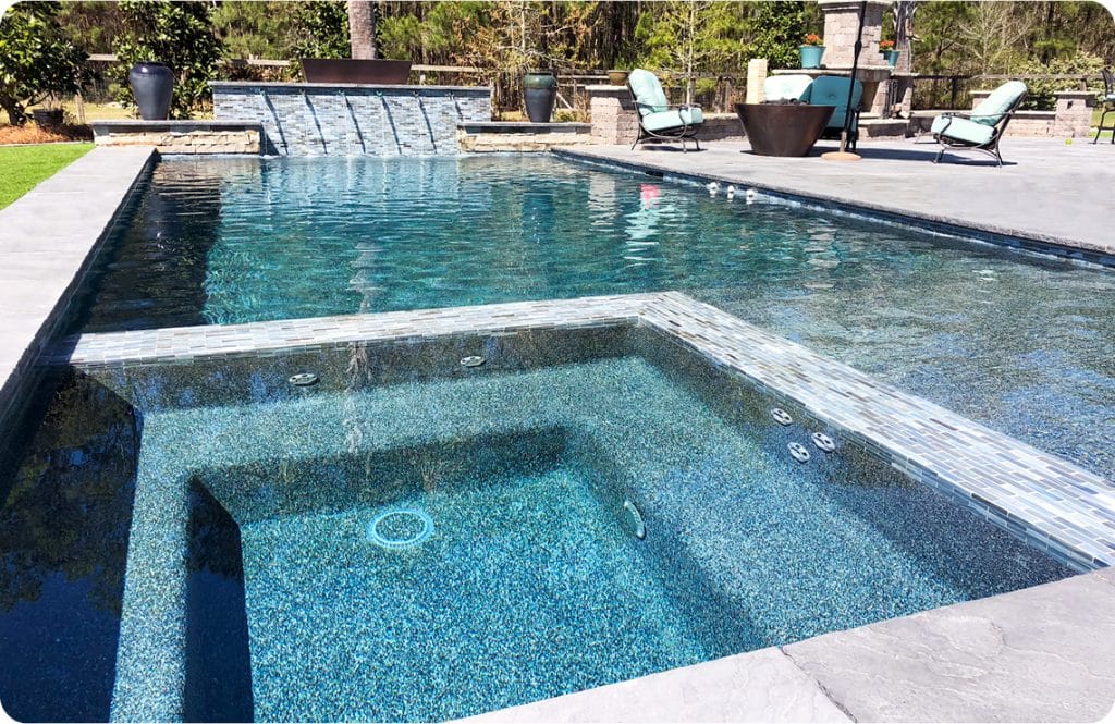 Remodeled gunite pool with square interior spa and water features.