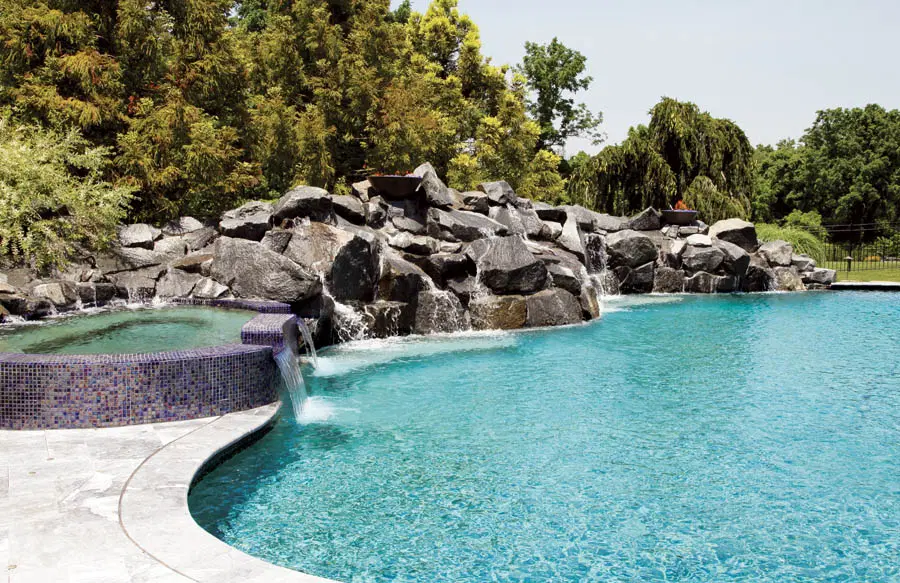 Rock waterfall and tiled spa on a swimming pool.