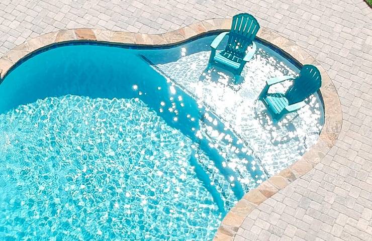 Swimming pool with tanning ledge and two chairs.