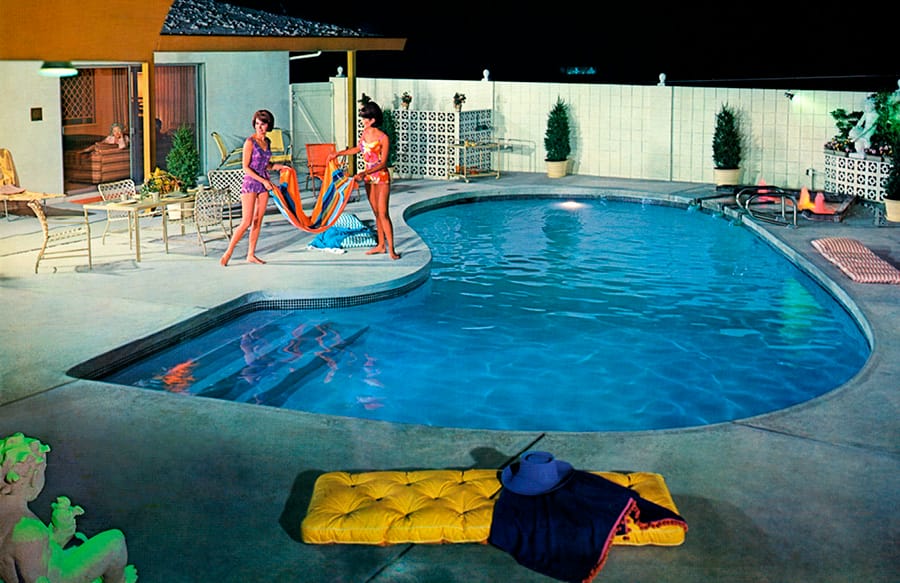 1960's-era women around a swimming pool at night.