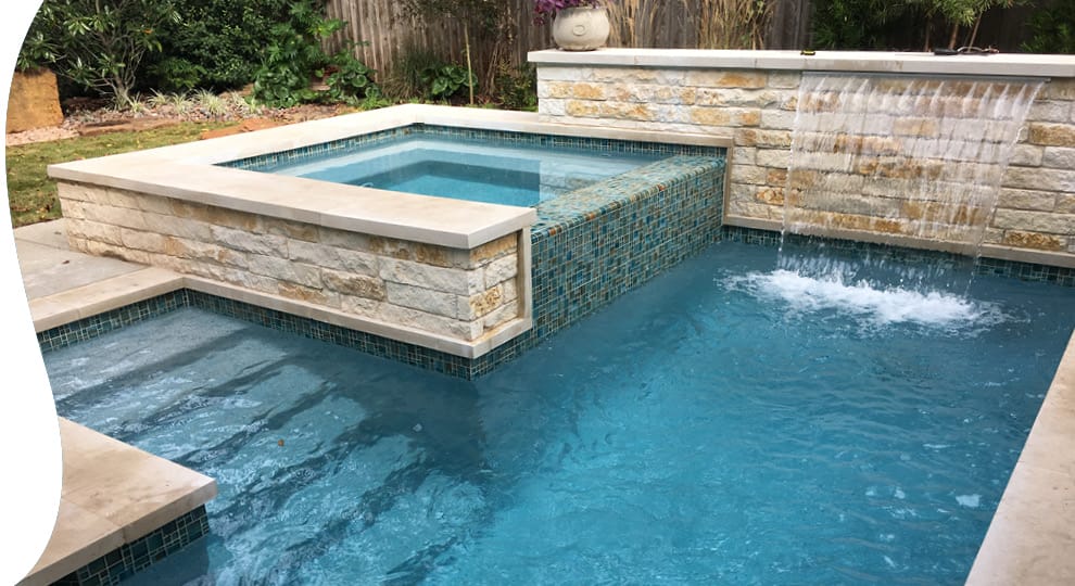 Custom pool with raised square spa and large cascading water feature.