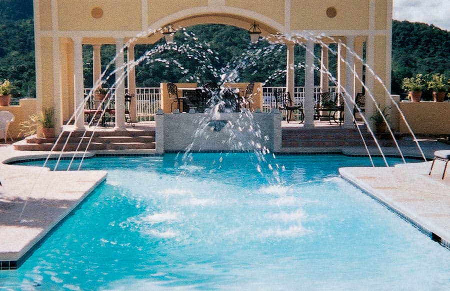 Swimming pool with eight laminars of water arcing over the surface.