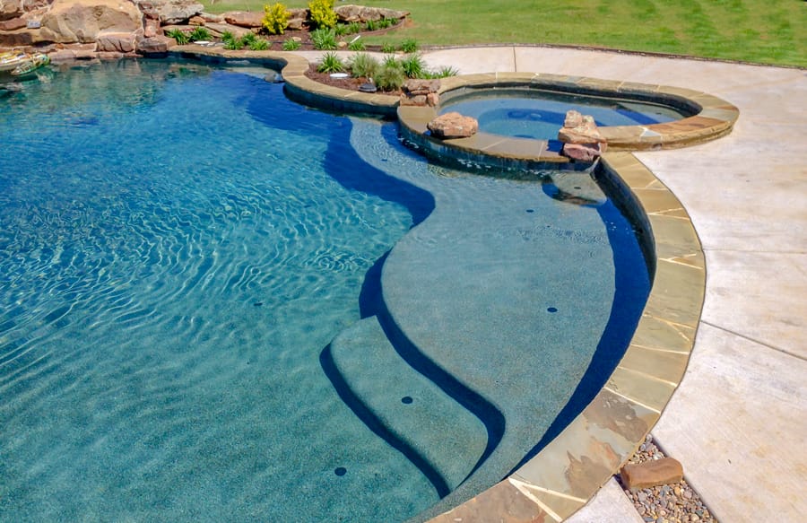 Inground pool and spa with flowing organic shape, flagstone coping, and accent rocks.