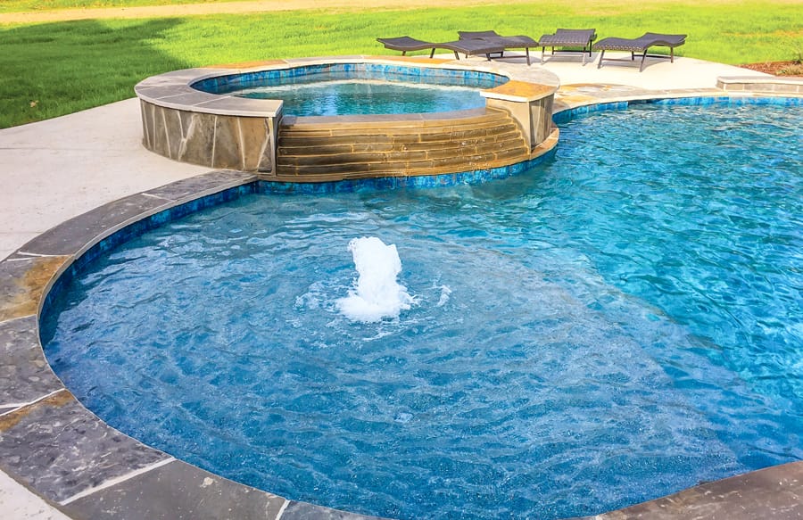 Spa and sun shelf on curvy swimming pool.