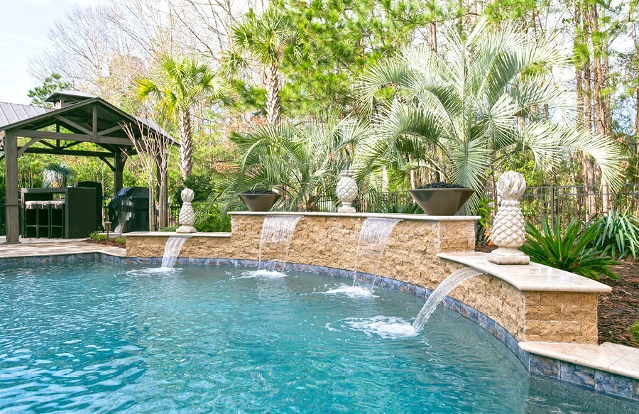 Inground pool with raised wall with four cascade water features.