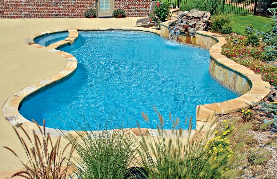 Free-form swimming pool with rock waterfall and small spa.