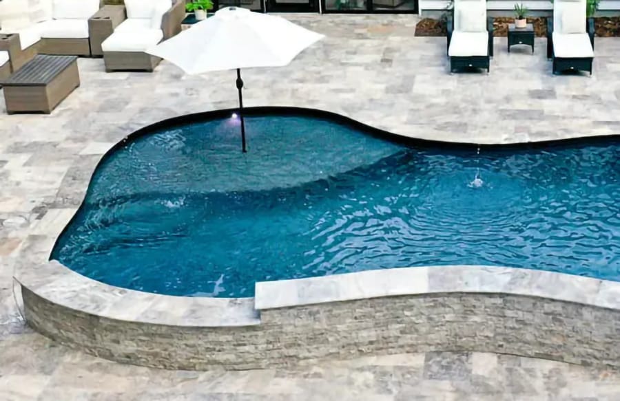 Curvy tanning shelf with integrated patio umbrella on gunite swimming pool,