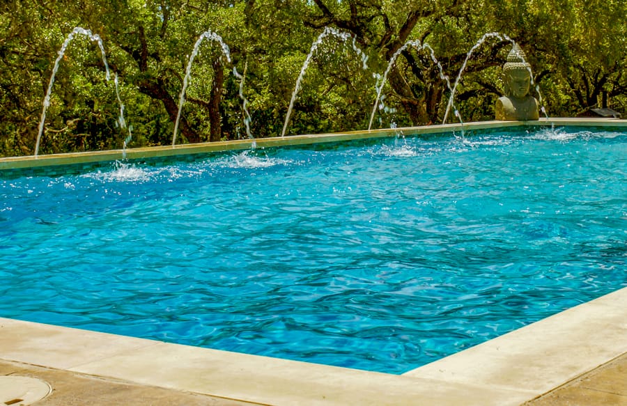 Five arcing deck jet fountains on rectangle pool.