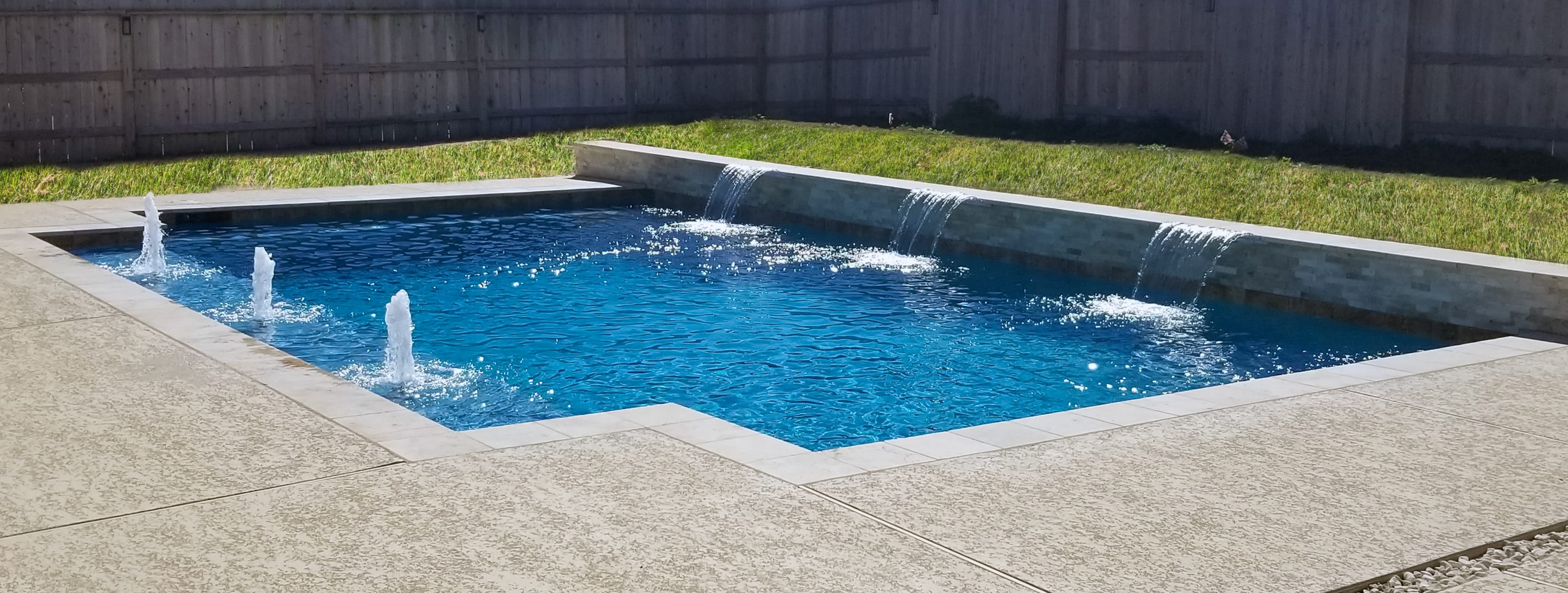 Geometric inground pool with bubbler fountains and cascade water features.