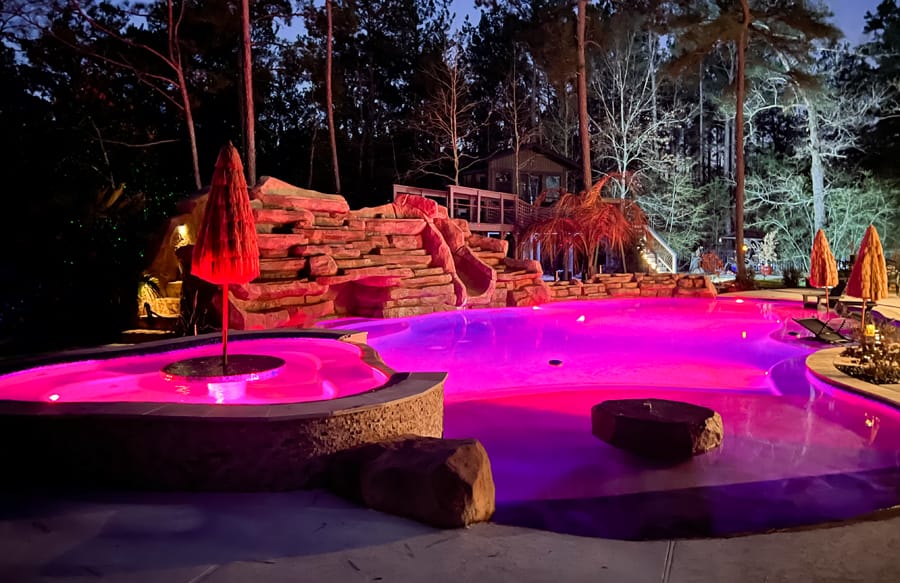 Lagoon-style pool illuminated in pink light.