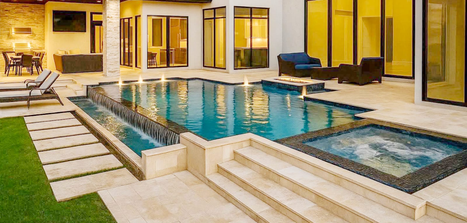 Sleek infinity edge pool & spa in backyard at sunset.