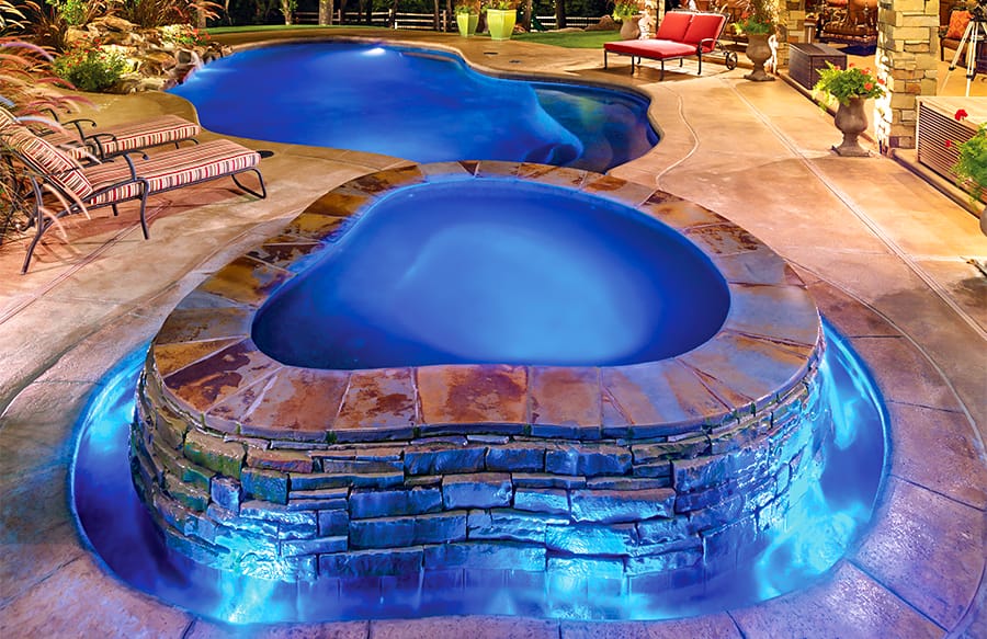 Organic-shaped pool & spa lit in blue light.
