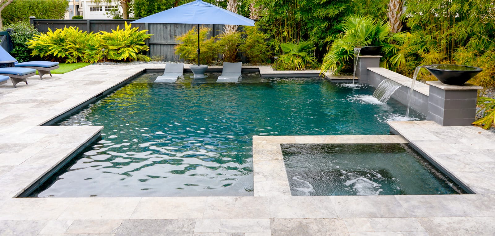Interior spa on a geometric pool with a tanning ledge and cascade waterfall features.