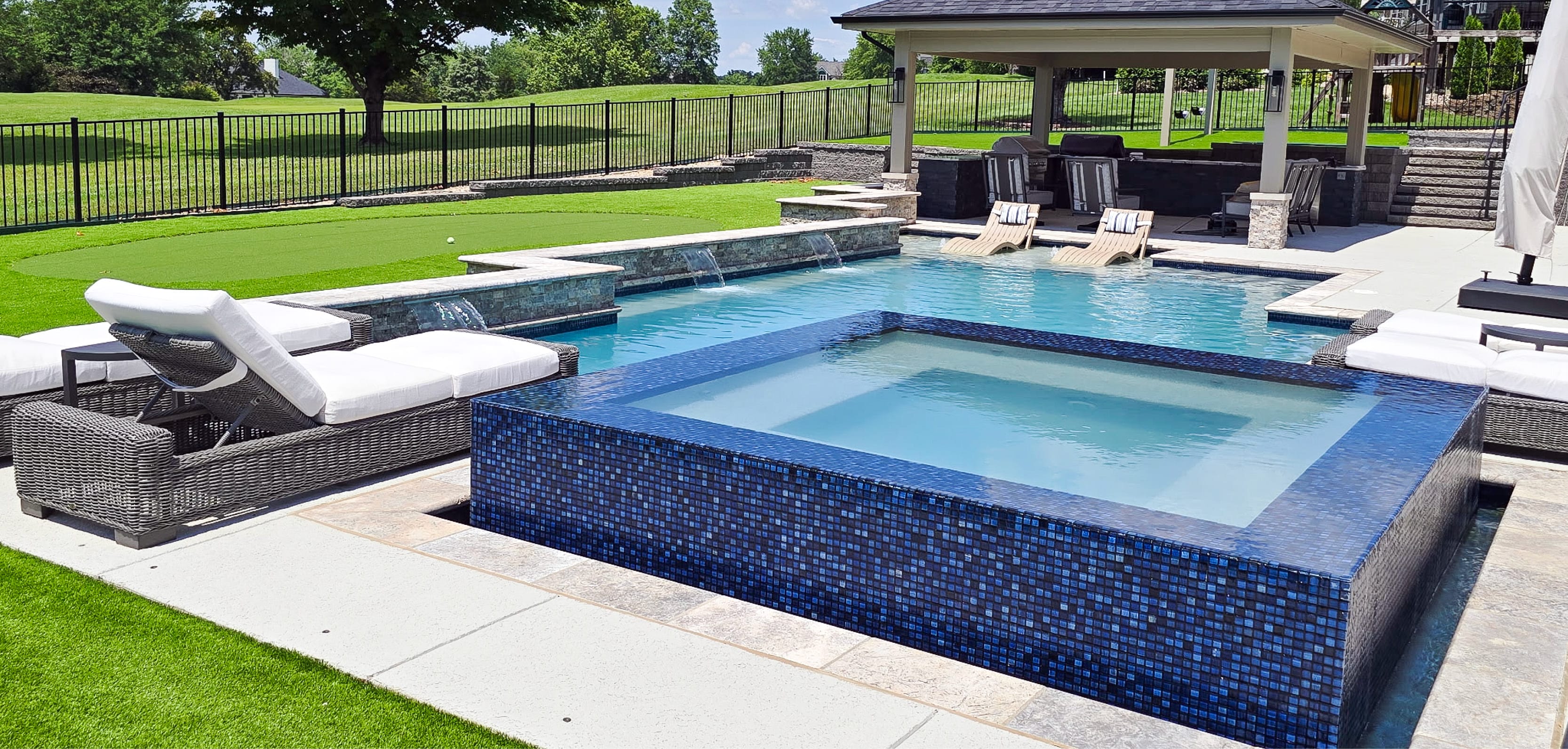 Backyard with pavilion-covered lounge area and a gunite pool with a sleek rim-flow spa.