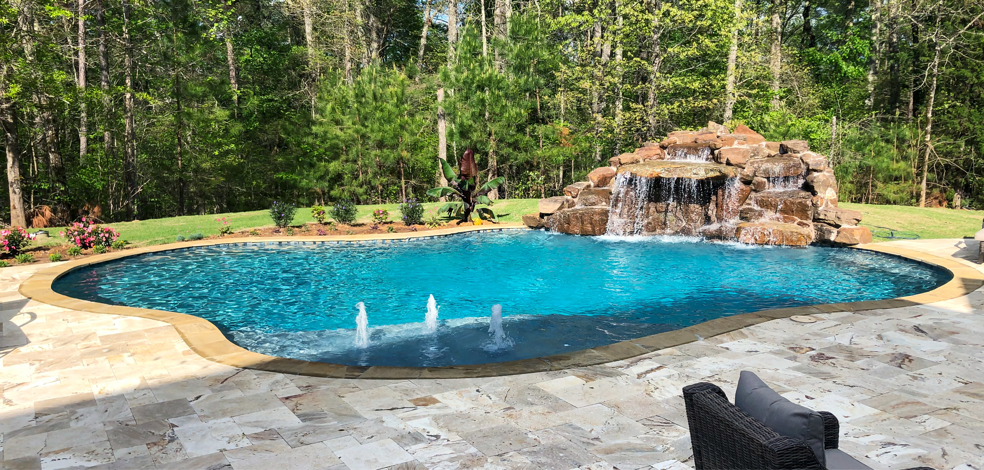 Naturalistic gunite pool with large rock waterfall and trio of bubbler fountains.