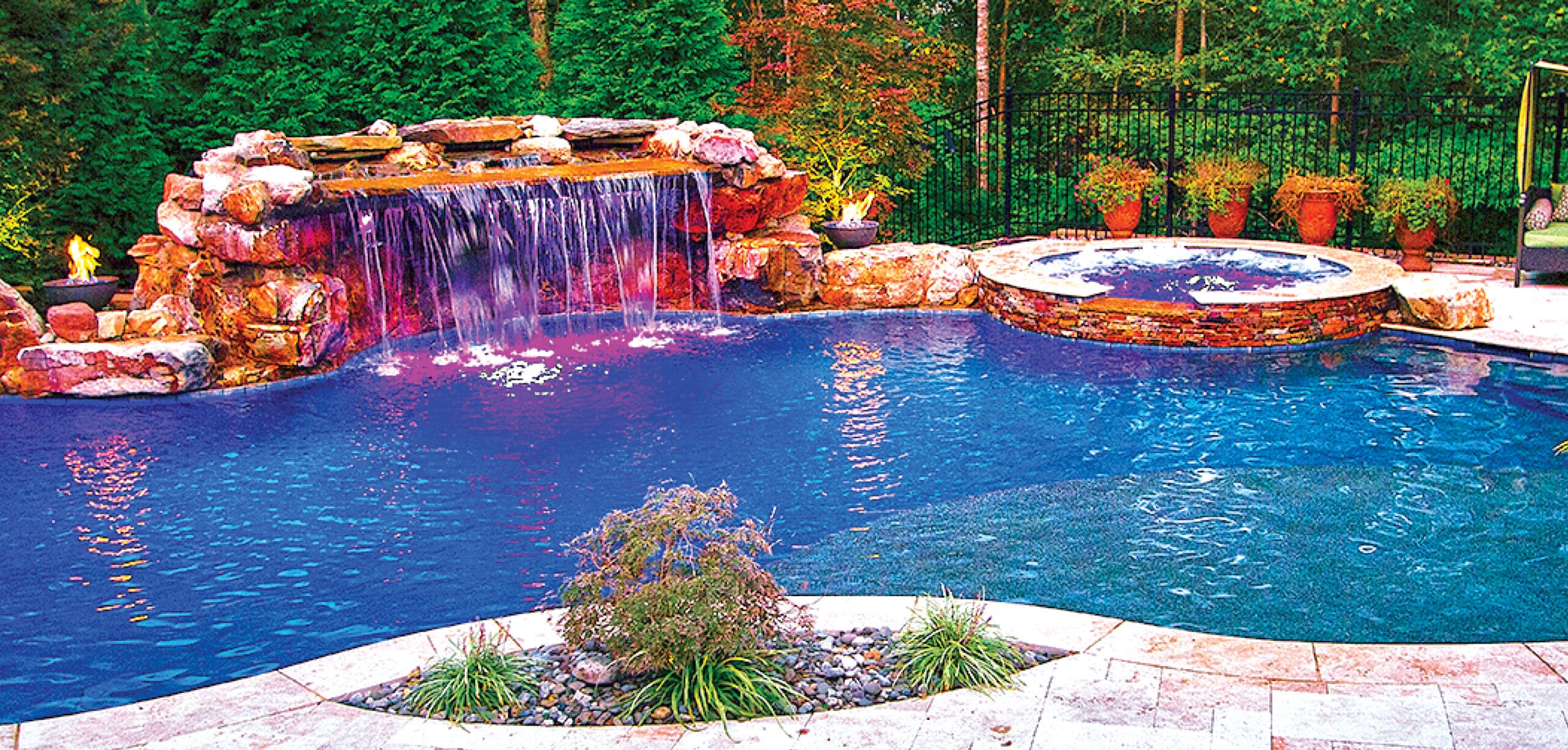 Stone grotto waterfall on swimming pool with integrated planter.
